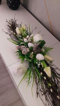 a bouquet of flowers sitting on top of a white table next to a vase filled with eggs