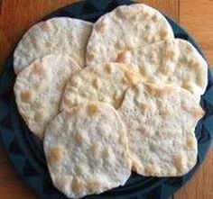 four pita breads sitting on top of a black plate next to a wooden table