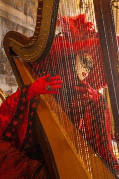 a woman dressed in red playing a harp with her hands and face painted like clowns