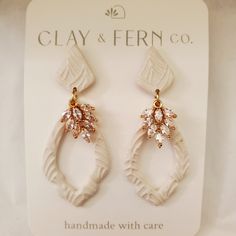 a pair of white earrings with pink stones on it's earring hooks in front of a sign that says clay & fern co