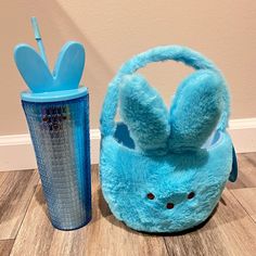 a blue stuffed animal bag next to a cup on the floor with toothbrushes in it