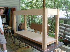 a man standing in front of a bed frame made out of plywood and wood