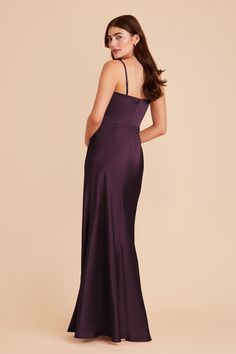 a woman in a long purple dress looking back at the camera and wearing a halter top