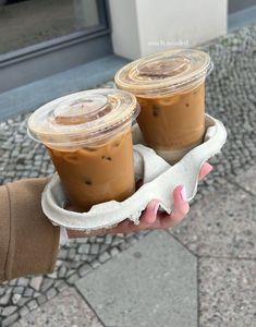 two cups of coffee are held in one hand