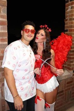 a man and woman dressed in costumes posing for the camera with red feathers on them