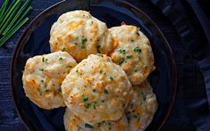 some biscuits are on a black plate with green onions