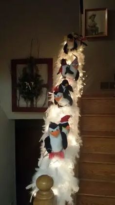 several stuffed penguins are lined up on a stair case with lights strung down the side