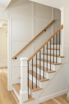 a white staircase with wooden handrails and black rails