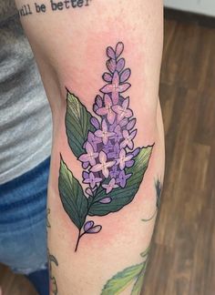 a woman with a tattoo on her arm has a purple lilac flower and green leaves