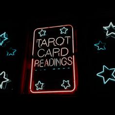 a neon sign that says tarot card readings in white and blue stars around it