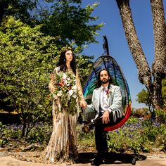 a man and woman are dressed up in wedding attire sitting on a hammock