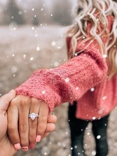 two people holding hands in the snow with one woman's hand on the other