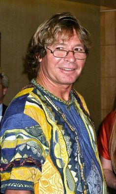 a man wearing glasses and a colorful shirt is standing in front of a group of people