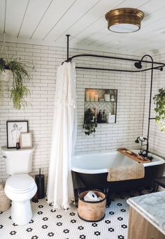 a bathroom with a white brick wall and black bathtub next to a toilet in the corner