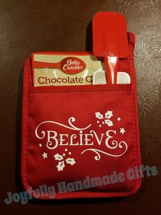 a red bag with white lettering on it and a spatula in the pocket that says believe