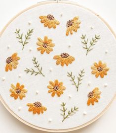 an embroidery project with yellow daisies and green leaves