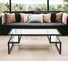 a living room with a couch, coffee table and large windows