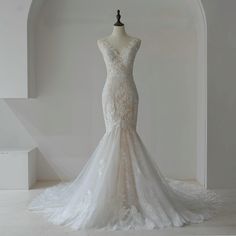 a wedding dress is displayed on a mannequin in front of a white wall