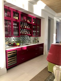 a kitchen with red cabinets and wine glasses on the counter top, along with a lamp