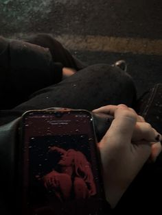 a person is sitting on the ground with their cell phone