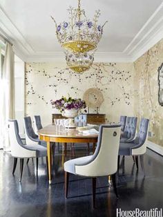 a dining room table with chairs and a vase on it's centerpiece in front of a floral wallpaper