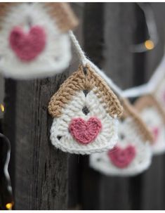 crocheted ornaments hanging from a wooden fence with string lights in the shape of hearts