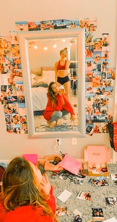 a woman sitting in front of a mirror on top of a counter next to a bed