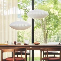 a dining room table with four chairs and two lamps on top of it, in front of a large window