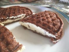 two chocolate waffles on a plate with one cut in half to show the inside