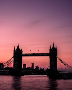 the tower bridge is silhouetted against an orange and pink sky at sunset in london, england