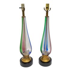 two colorful glass vases sitting next to each other on top of a wooden stand