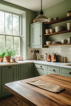 a kitchen filled with lots of green cabinets and wooden counter top next to a window