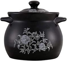 a black pot with flowers painted on the front and side, sitting next to a white background