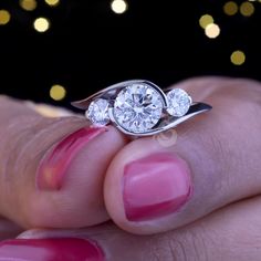 a woman's hand holding a diamond ring with two diamonds on the top and bottom