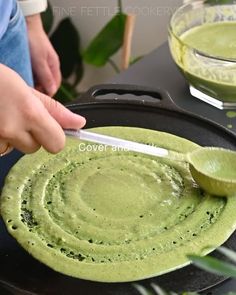 a person using a spoon to dip green sauce into a skillet