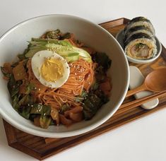 a bowl of noodles with an egg on top and chopsticks next to it