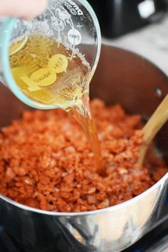 someone is pouring some liquid into a pot full of food that has been cooked on the stove