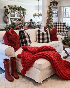 a living room filled with white furniture and red pillows on top of each other's blankets