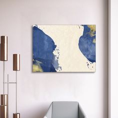 an abstract painting hangs on the wall next to a chair