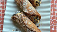 two crepes on a white plate with blueberries and powdered sugar sprinkled on top