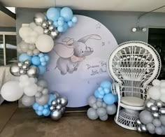 an elephant balloon arch with blue and silver balloons on it's sides, next to a white wicker chair