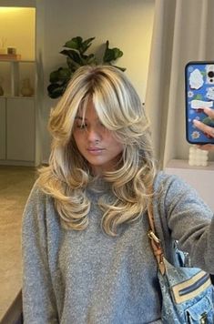 a woman taking a selfie with her cell phone in front of her face and wearing a gray sweater