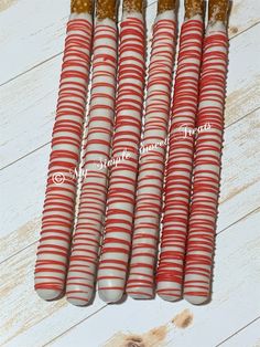 six red and white striped candy canes sitting on top of a wooden table next to each other