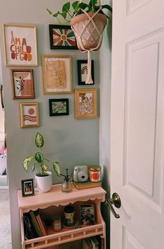 there is a pink shelf with pictures on the wall next to it and a potted plant