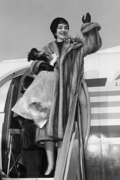 a woman in a fur coat getting off an airplane