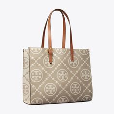 T Monogram is a classic pattern inspired by Pennsylvania Dutch quilting. The collection speaks to the timelessness of great style.  The tote is crafted in contrast embossed leather with an adjustable shoulder strap. Each side of the tote features an inverse color combination, creating two looks in one. Lined in soft microsuede with an interior laptop sleeve, every detail is considered, with special attention to function and versatility.   Crafted in partnership with a Leather Working Group-certi Classic Shoulder Bag With Double Handle And Embossed Logo, Classic Shoulder Bag With Embossed Logo For Shopping, Beige Monogram Print Bag For Everyday Use, Elegant Shoulder Bag With Monogram Print And Coated Canvas, Classic Tan Coated Canvas Shoulder Bag, Elegant Shoulder Bag With Monogram Print, Classic Bags With Monogram Print In Coated Canvas, Classic Tan Monogram Canvas Shoulder Bag, Classic Top Handle Bag With Monogram Print