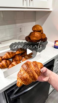 croissants are being held up in front of the oven