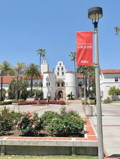 a red flag is hanging from a lamp post in front of a large white building