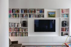 a living room with bookshelves and a flat screen tv mounted on the wall