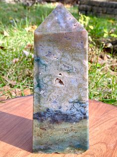 a piece of stone sitting on top of a wooden table next to grass and trees